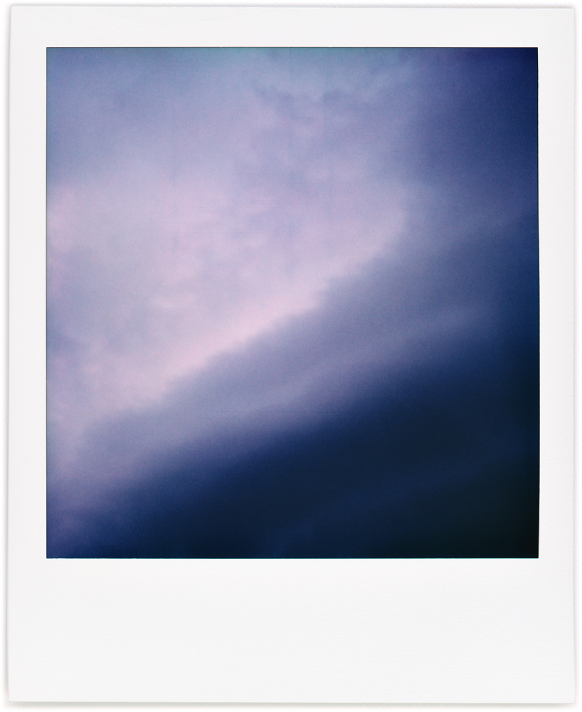 Polaroid abstract photograph of bands of dark storm clouds forming in the evening.
