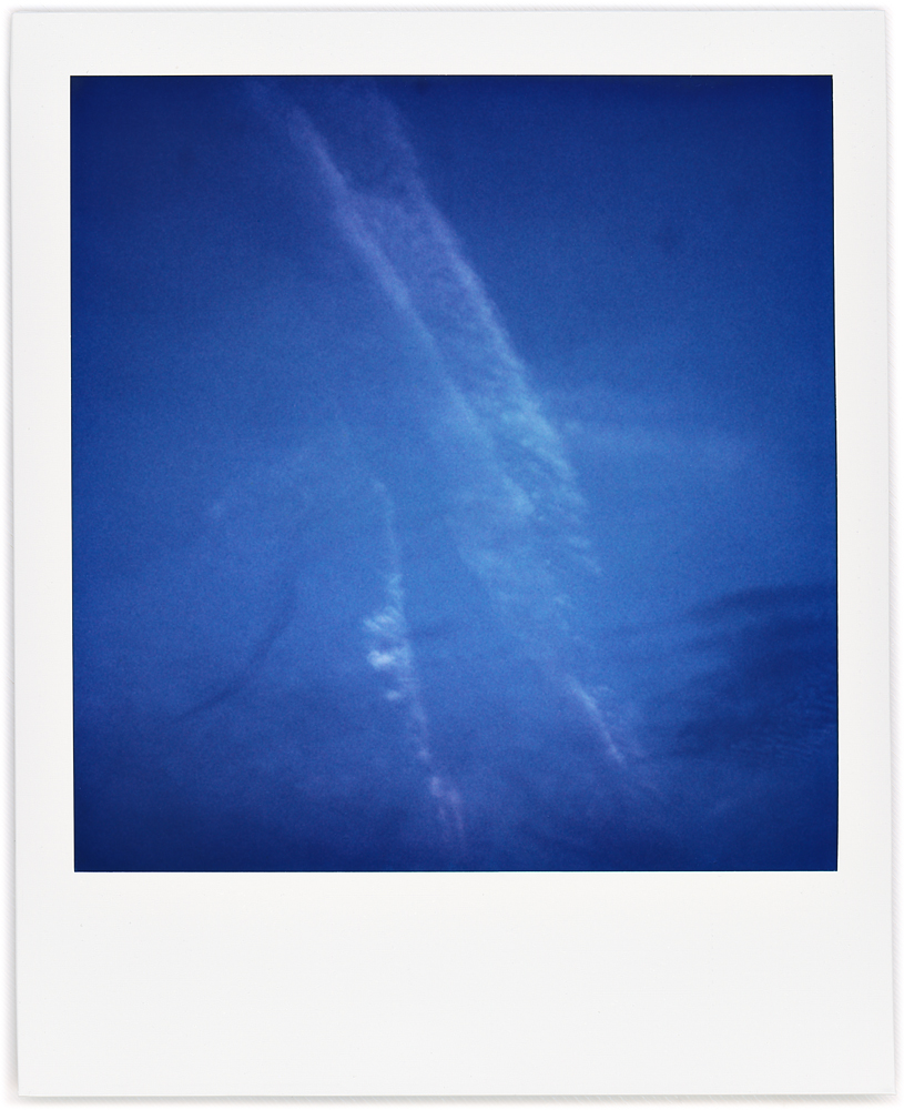 Polaroid abstract photograph of condensation trails from airplanes in the early morning sky.