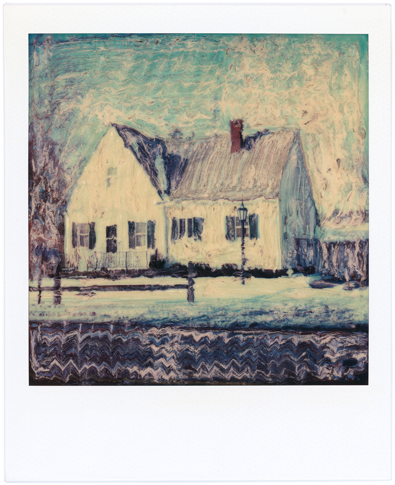 Polaroid SX-70 manipulation photograph of a white cape cod house on a winter day with snow.